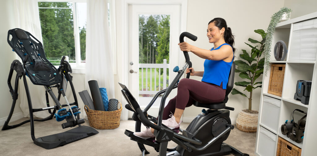 Person working out in home gym with Teeter FreeStep, Inversion Table, and more fitness products.