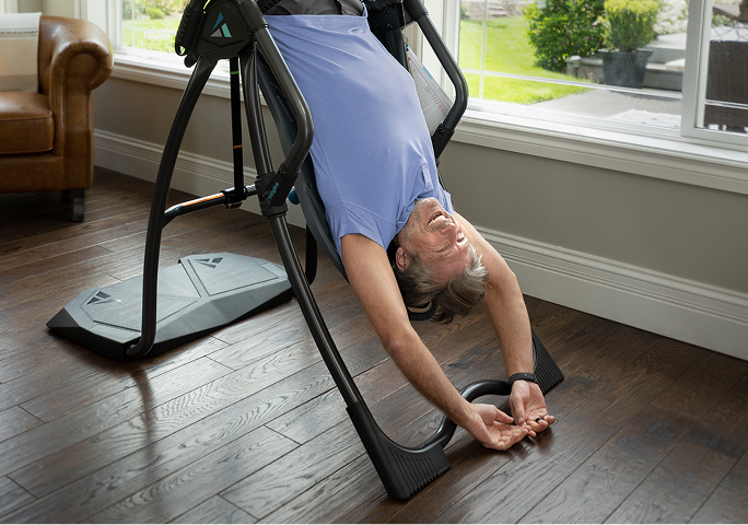 Man using an inversion table for back stretching and relaxation indoors