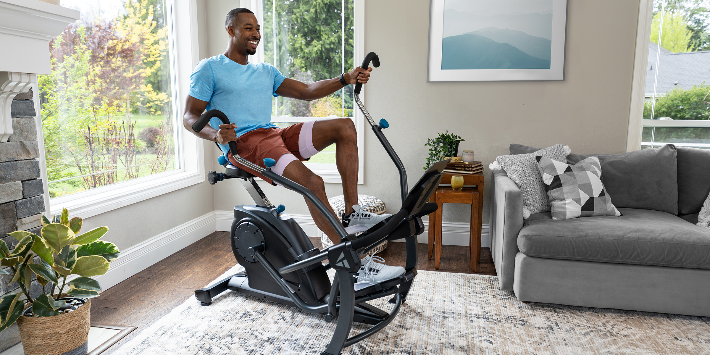 A man is using a Teeter FreeStep Recumbent Bike for a workout in his living room.